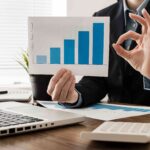 businessman-doing-ok-sign-while-holding-growth-chart-min